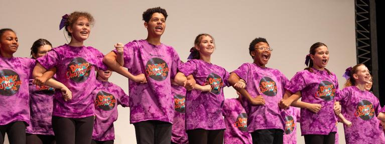 Students looking arms performing on stage