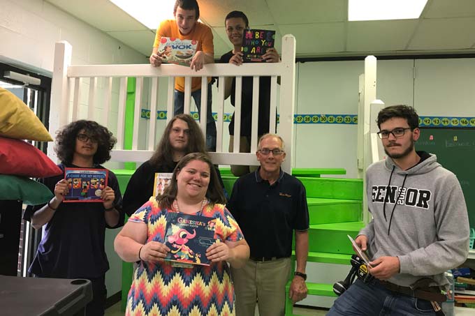 Heritage CTE students standing with books around reading loft