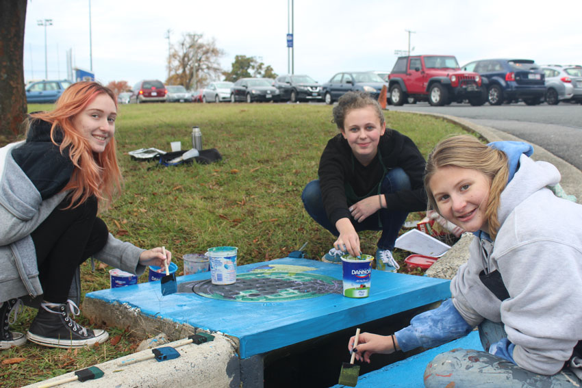 Three students painting storm drain