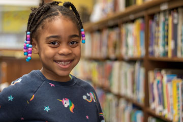 Elementary age girl smiling in school library