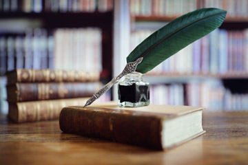 Quill on old book in library