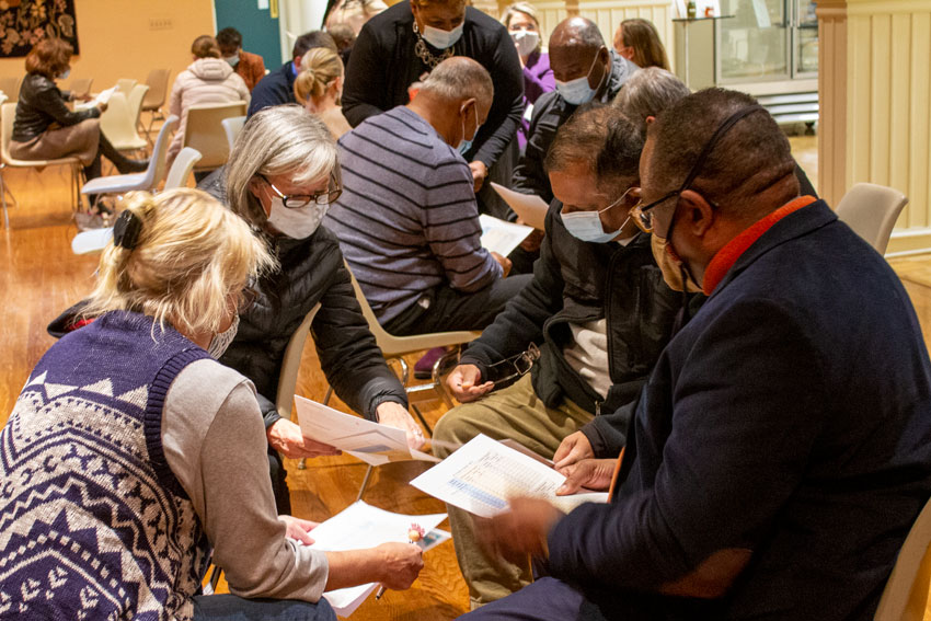 Community members working in groups in large room