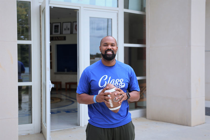 Jamar Lovelace holding football outside school