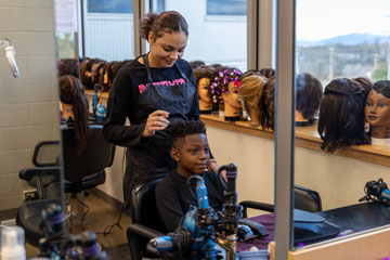 Cosmetology student cutting elementary student's hair