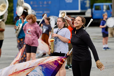 Color guard member smiling with band members in the background