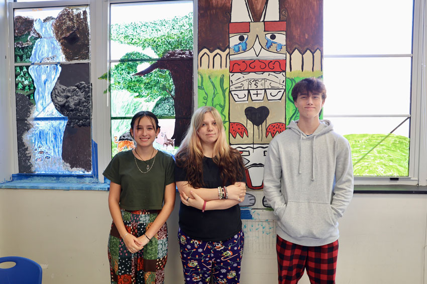 Three students standing in front of artwork