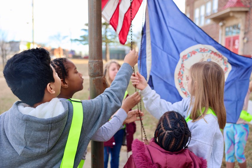 Group of students raising flags outside school