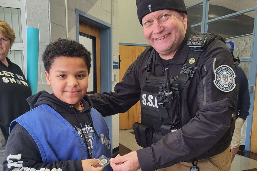 School security officer handing student a challenge coin