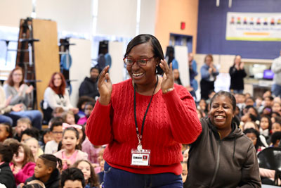 Teacher reacting to news of award during school assembly