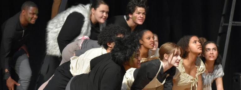 Students crouched on stage during play performance