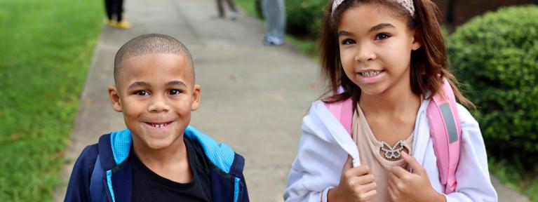 Two students with backpacks outside school